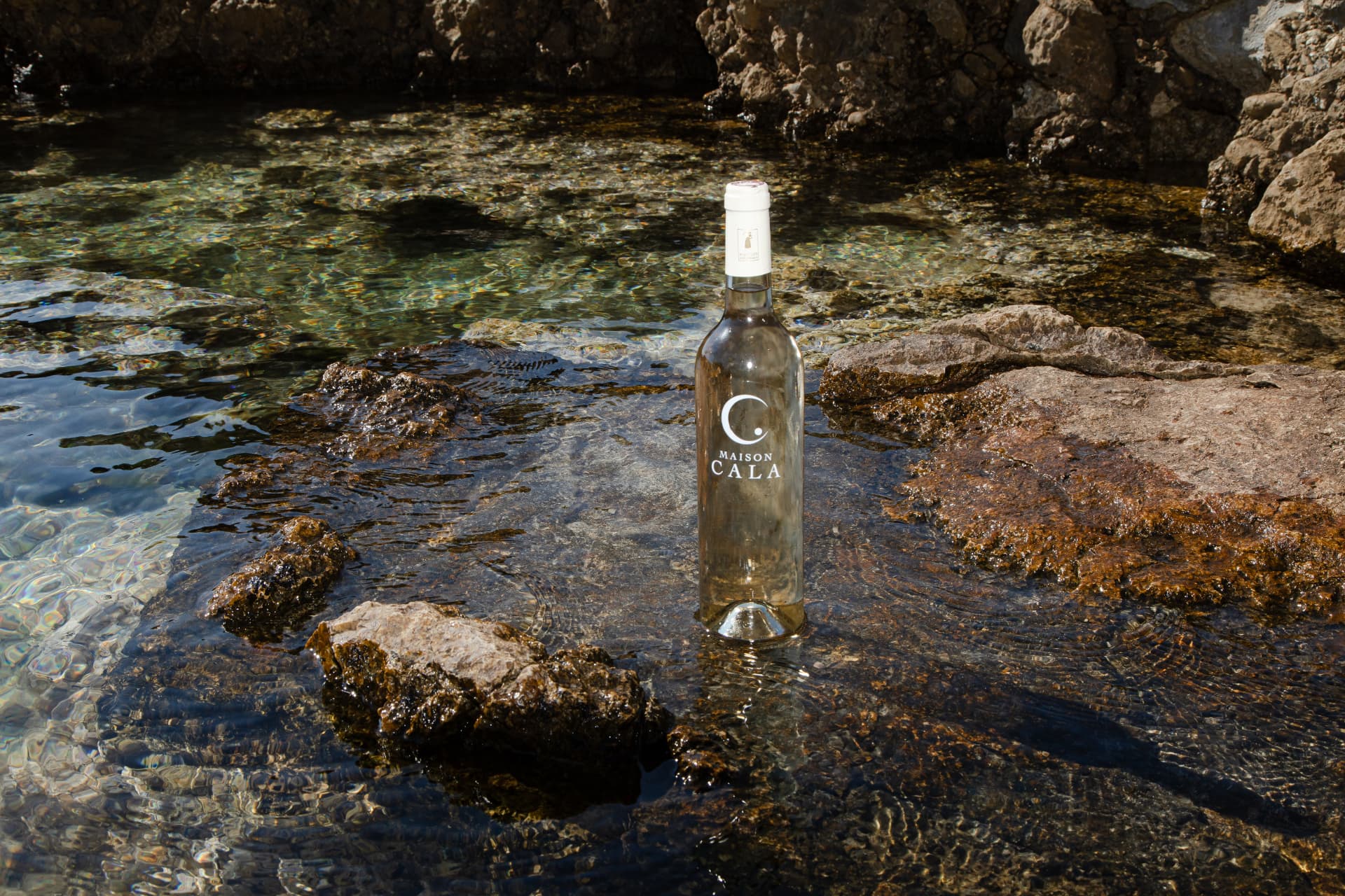 Maison Cala Rosé bottle by the Mediterranean water
